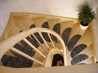 halbgewendelte Treppe in Ahorn mit Stufeneinsätzen aus Stein